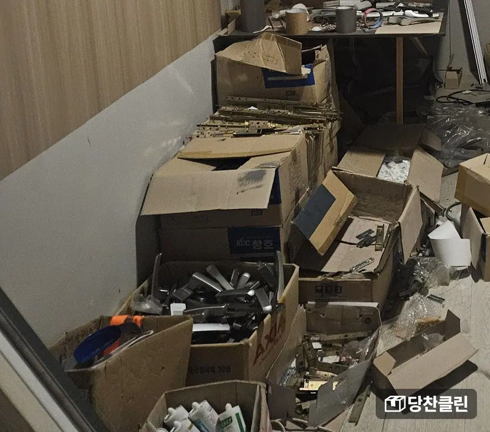 문 손잡이와 경첩 같은 철물이 담긴 종이 상자가 줄지어 놓인 창고