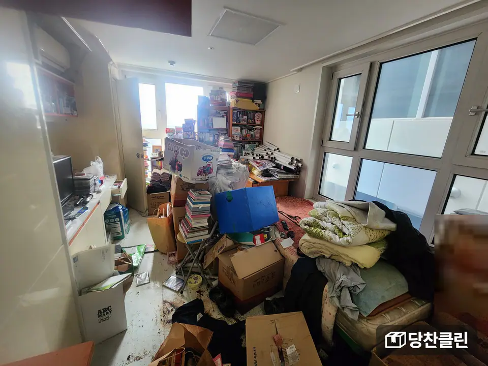 책과 상자, 이불과 매트리스가 방 안쪽까지 쌓인 원룸